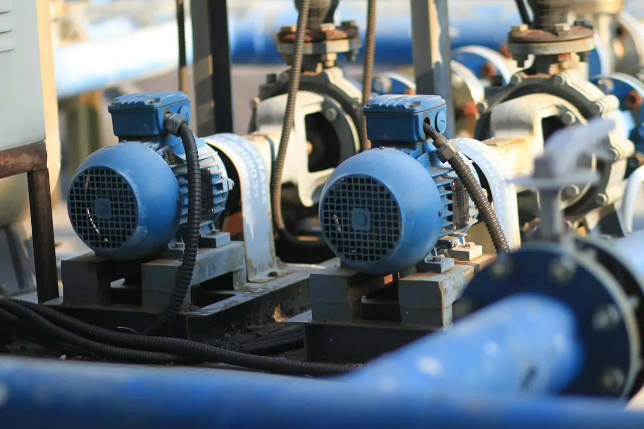 Two blue electric pump motors mounted on skids beside process pipework