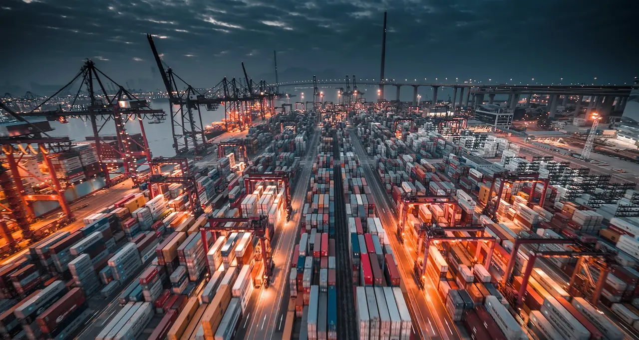 Container terminal at dusk, stacks lit by yard lighting